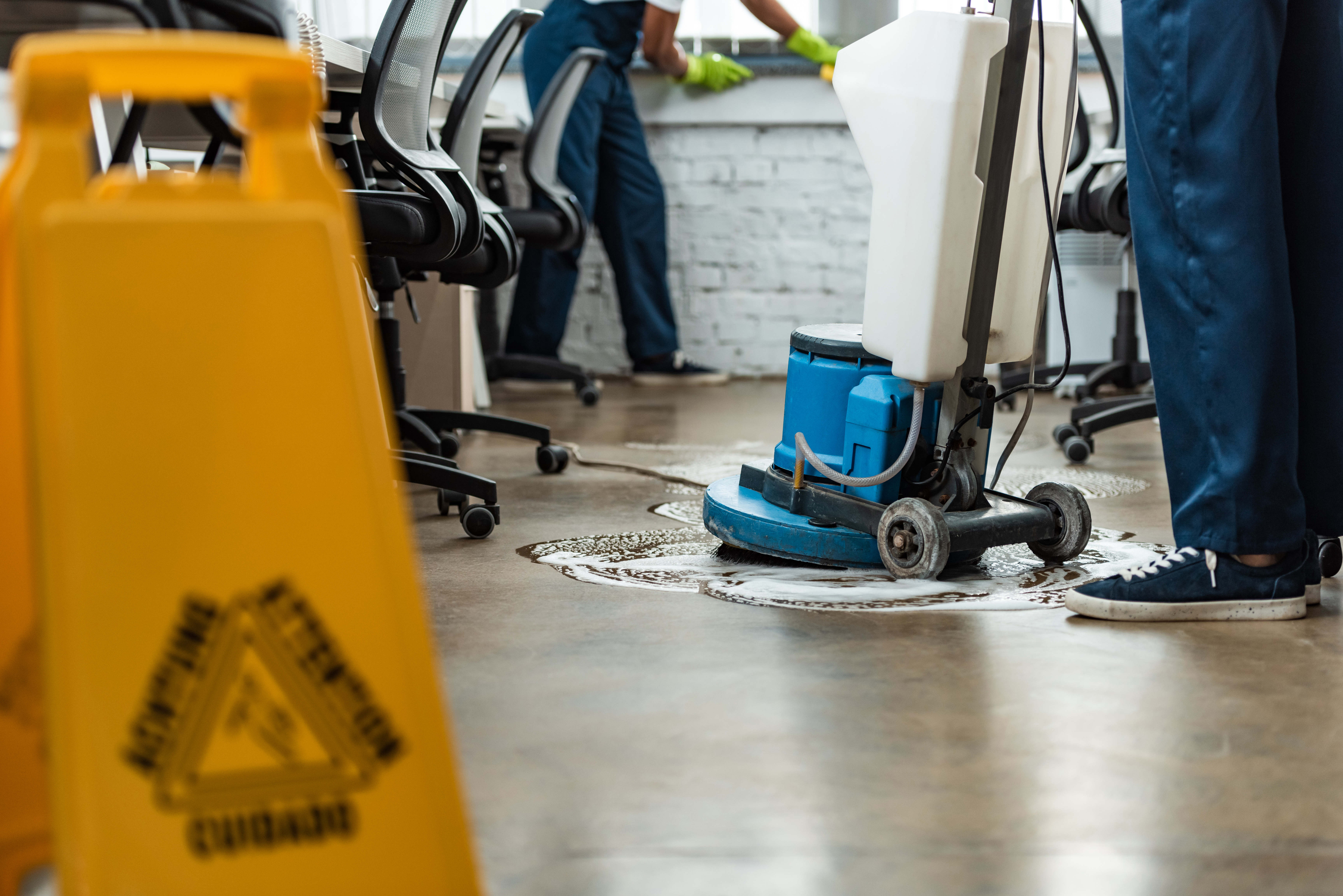 cropped view of cleaner washing floor with cleaning machine near colleague